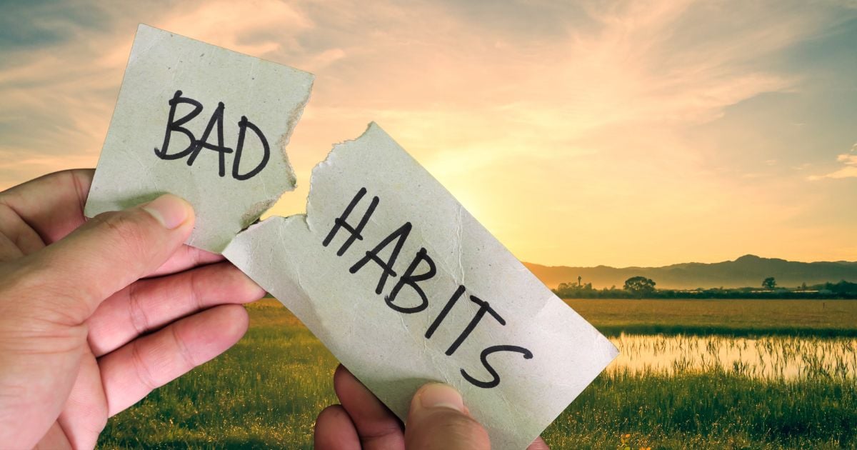 Morning scene with a closeup of hands holding a piece of paper with 'bad habits' written on it and torn in half